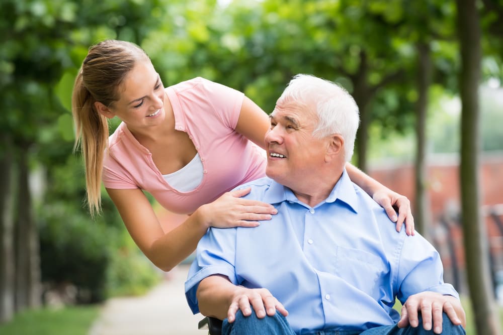 Teen Women Smiling Towards Looking Elder Care Man in Wheelchair